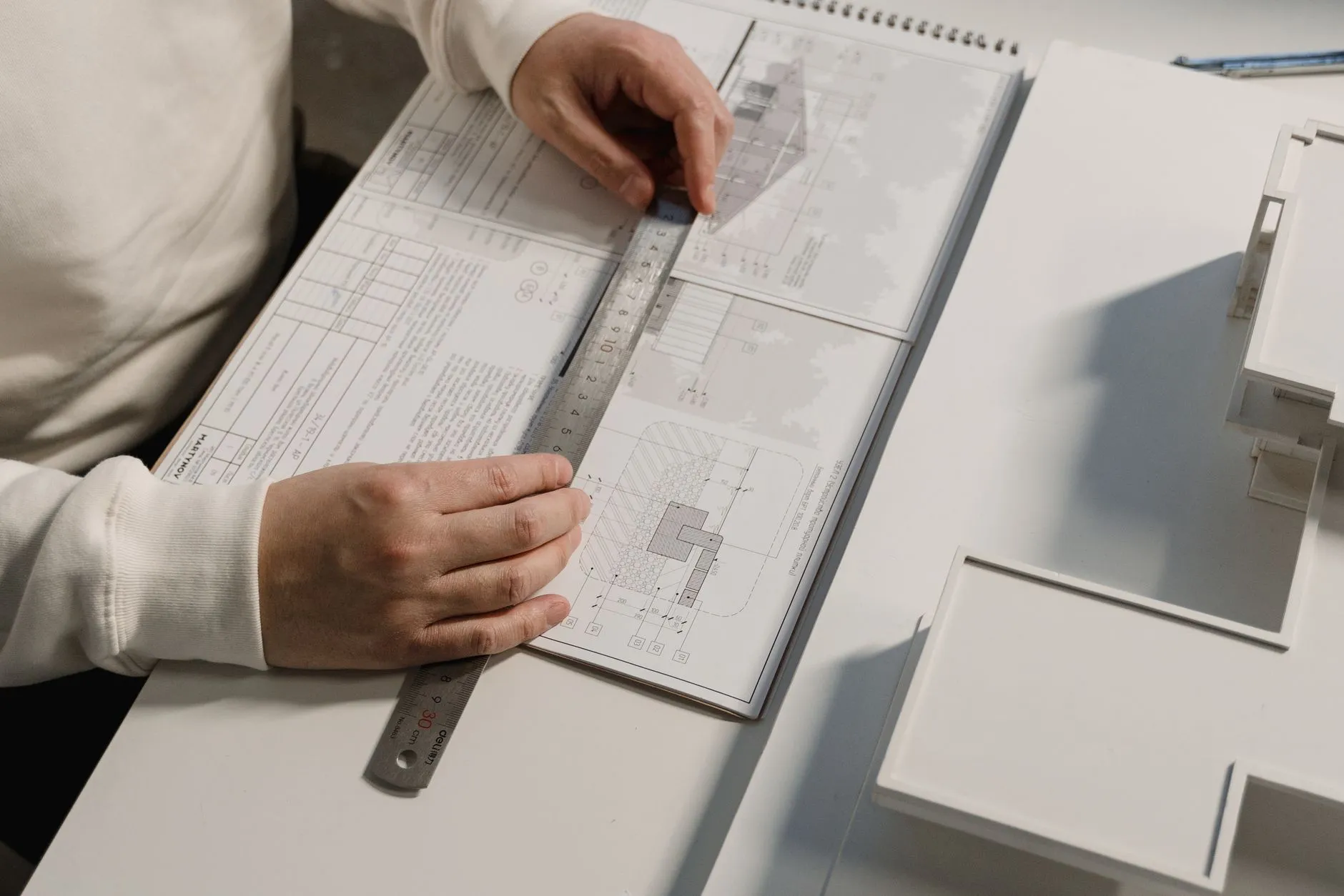 Hands squaring a ruler across a set of technical drawings