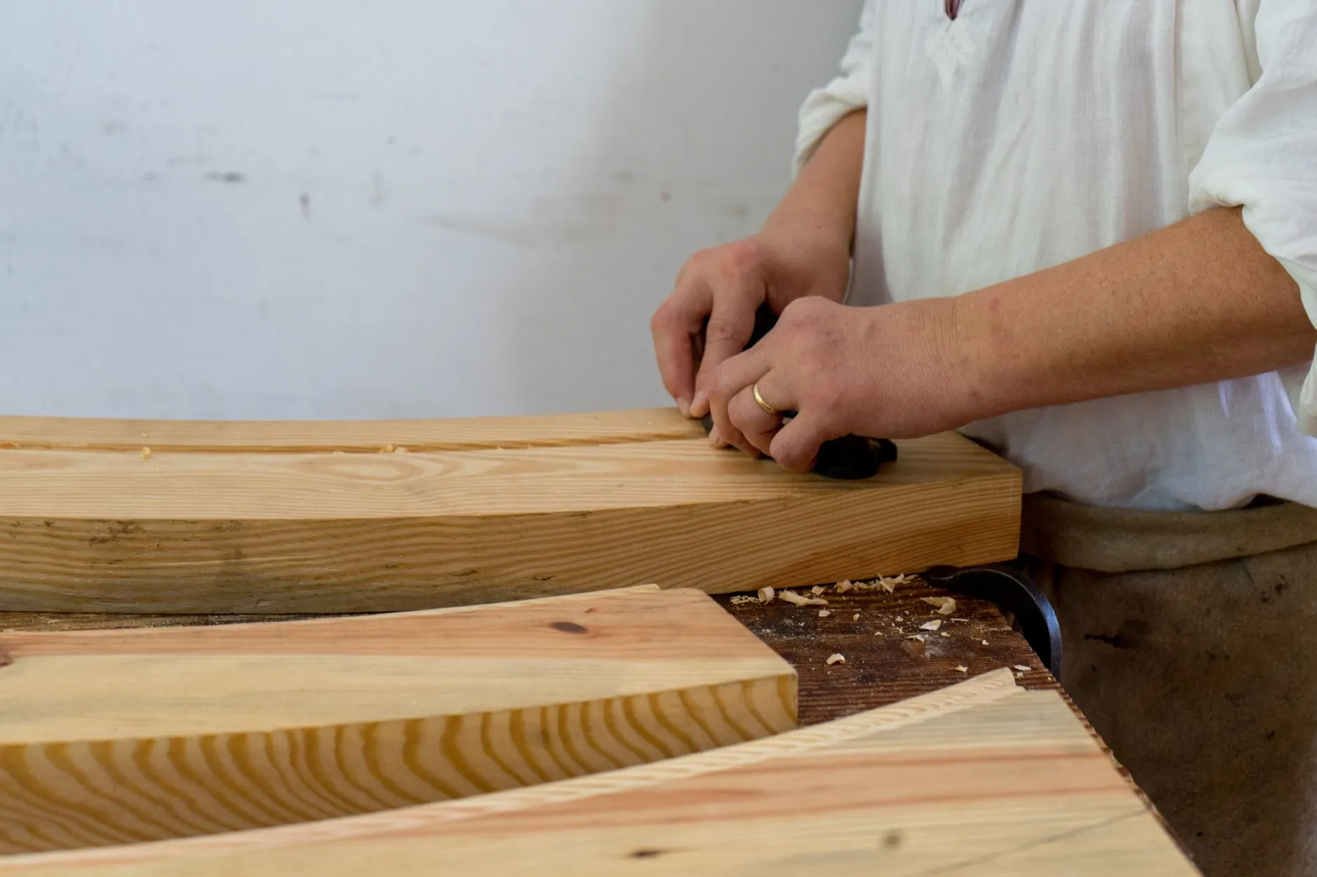 A maker running a hand along a planed board at the bench